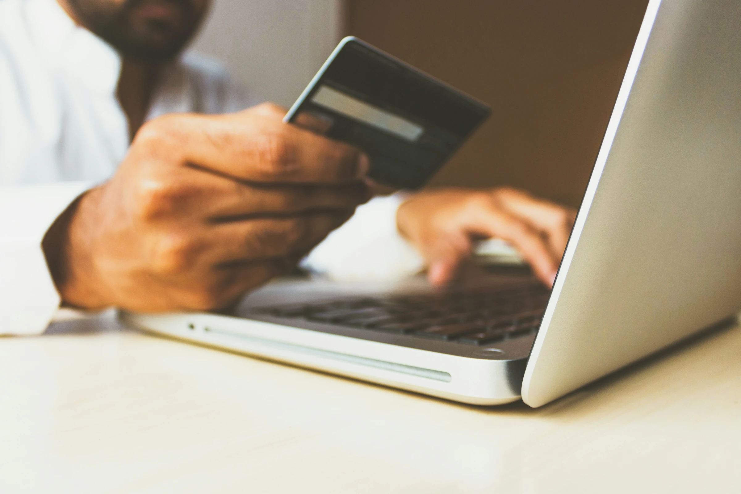 A shopper using a payment card and laptop to make an online purchase