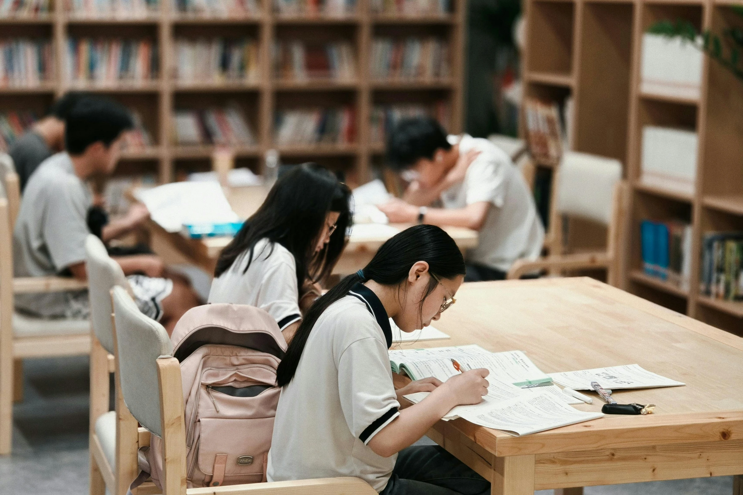 Students studying together at desks surrounded by library bookshelves