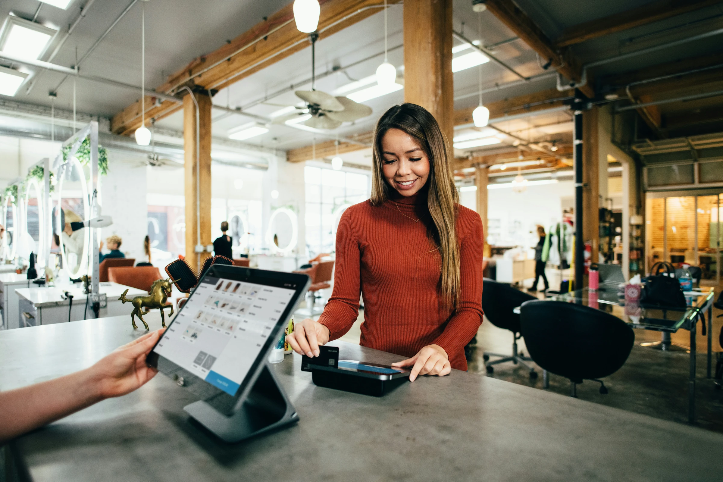 A customer paying by card at a staffed point-of-sale counter